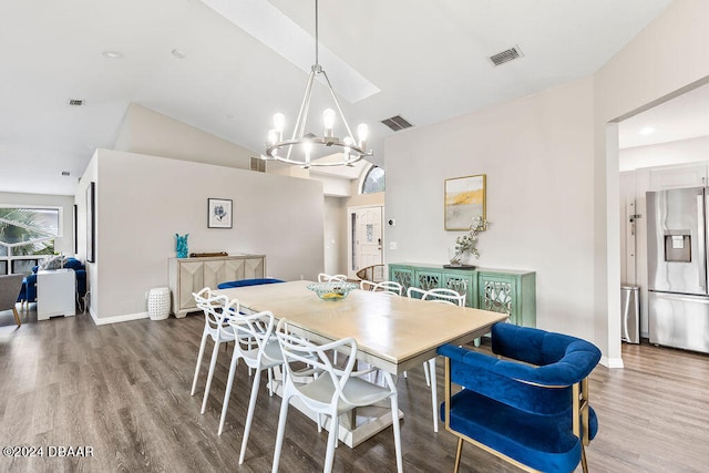 dining area featuring hardwood / wood-style flooring, vaulted ceiling, and an inviting chandelier