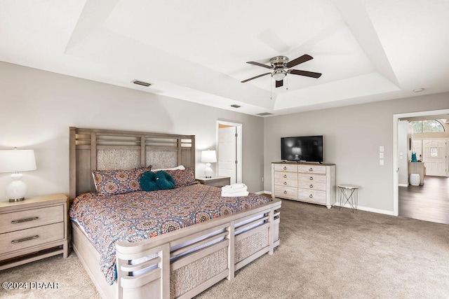 bedroom with carpet floors, ceiling fan, and a raised ceiling