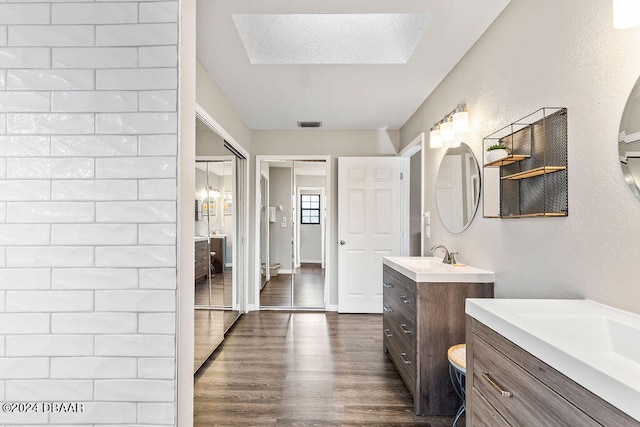 bathroom with hardwood / wood-style flooring, vanity, and a skylight