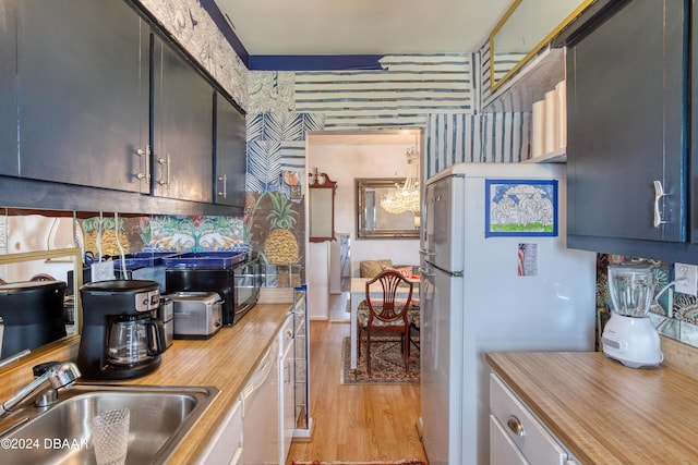 kitchen featuring butcher block counters, sink, white appliances, and light hardwood / wood-style flooring