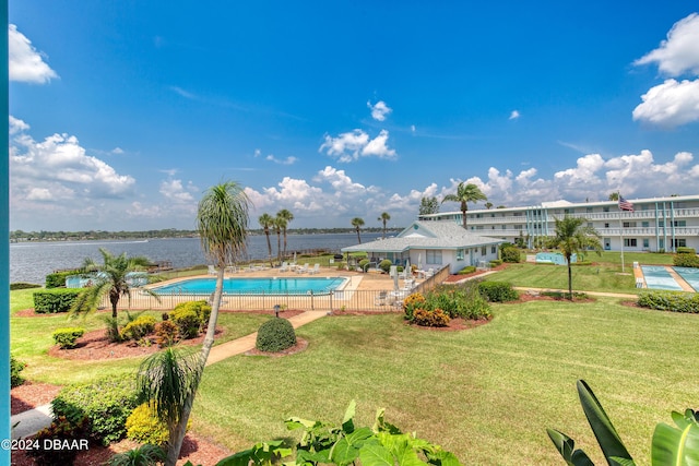 view of swimming pool featuring a water view, a yard, and a patio area