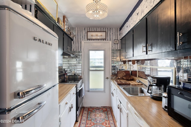 kitchen with white cabinetry, sink, white appliances, and a notable chandelier