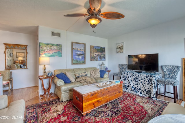 living room with wood-type flooring, a textured ceiling, and ceiling fan