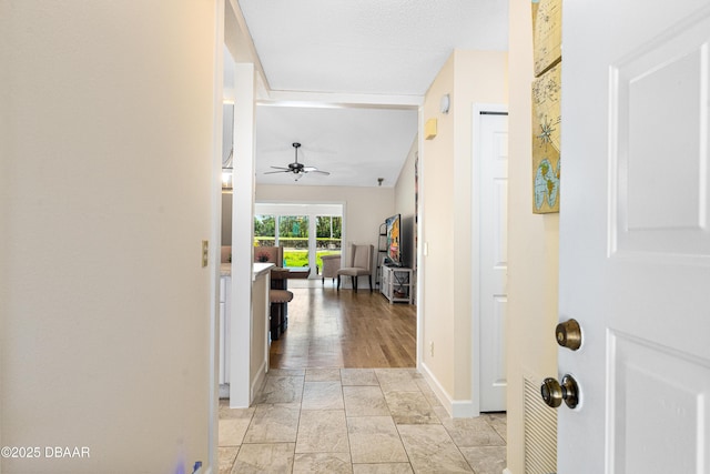 corridor with baseboards, visible vents, and vaulted ceiling