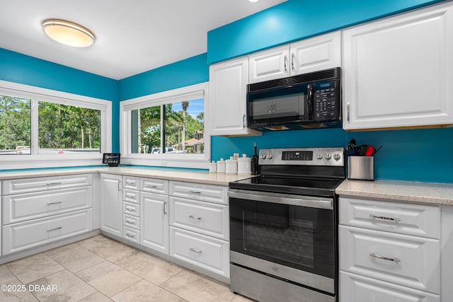 kitchen featuring white cabinetry, stainless steel electric range oven, light tile patterned flooring, and black microwave