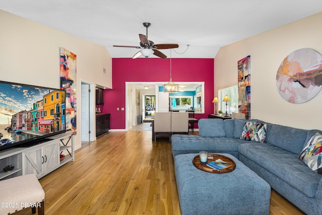 living area with ceiling fan, lofted ceiling, and light wood finished floors