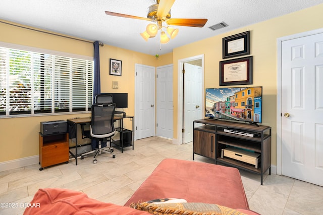 office with a textured ceiling, visible vents, baseboards, and ceiling fan
