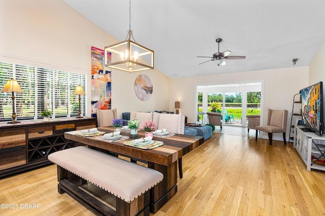 dining room with light wood-type flooring, vaulted ceiling, and ceiling fan with notable chandelier