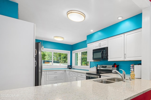 kitchen with recessed lighting, light stone counters, a sink, white cabinetry, and stainless steel appliances