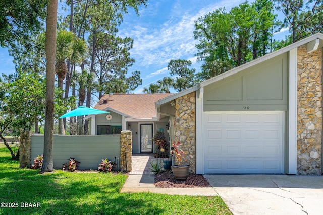 view of front of house with stone siding, driveway, an attached garage, and a front lawn