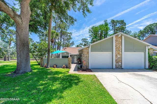 view of front of house featuring concrete driveway, stone siding, a front lawn, and an attached garage