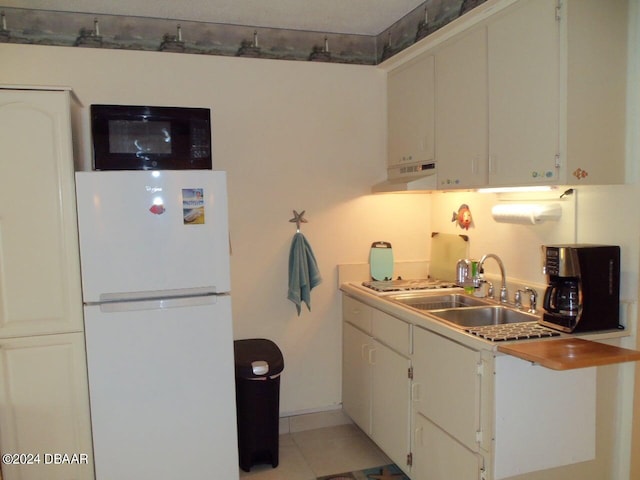 kitchen featuring light tile patterned flooring, sink, white fridge, and white cabinets