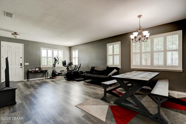 living room with dark wood-type flooring, a chandelier, and a textured ceiling