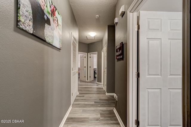 corridor with light hardwood / wood-style floors and a textured ceiling