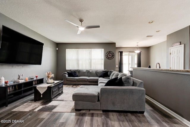 living room featuring a textured ceiling, hardwood / wood-style flooring, and ceiling fan