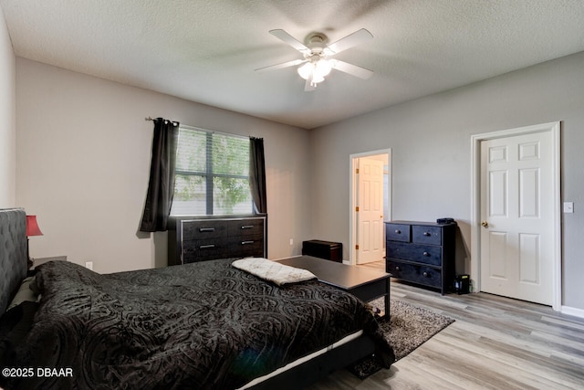 bedroom with ceiling fan, light hardwood / wood-style flooring, and a textured ceiling