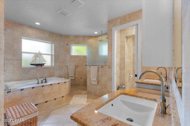 bathroom with tile patterned flooring, a textured ceiling, sink, and tile walls