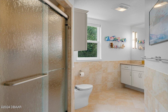 bathroom featuring toilet, vanity, tile walls, and a shower with door