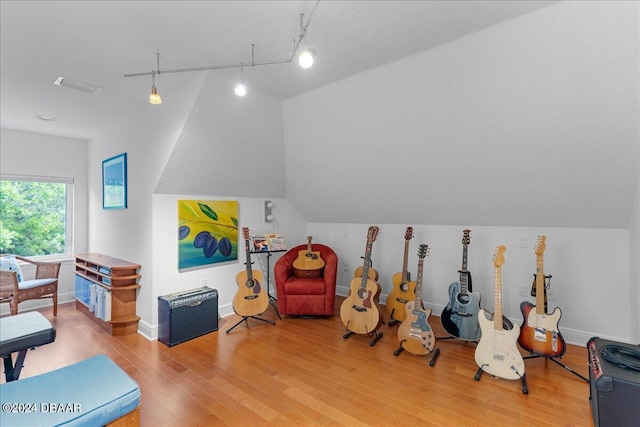 recreation room featuring wood-type flooring, a textured ceiling, track lighting, and lofted ceiling