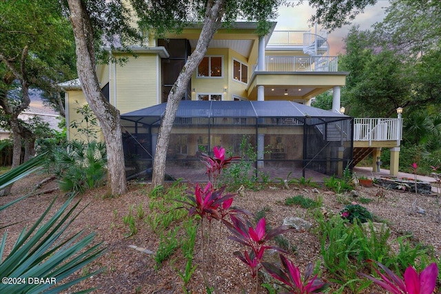 back house at dusk with a lanai and a balcony