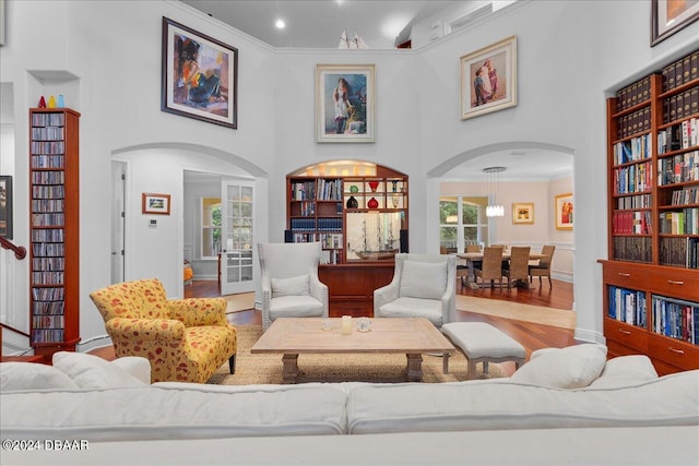 living room with hardwood / wood-style floors, ornamental molding, and a towering ceiling