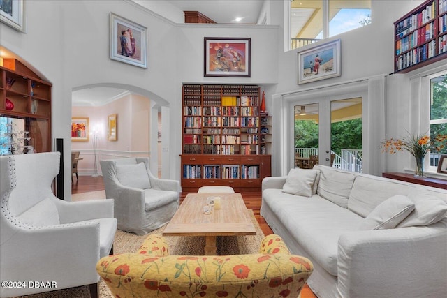 sitting room featuring french doors, a towering ceiling, hardwood / wood-style floors, and a healthy amount of sunlight