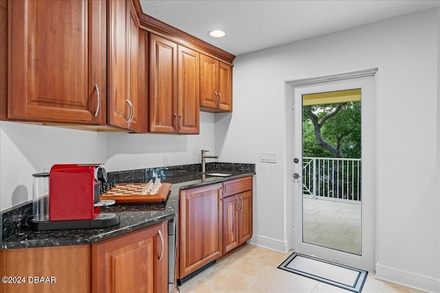 kitchen featuring dark stone counters, sink, and light tile patterned flooring