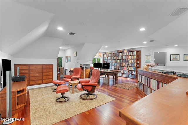 living room featuring lofted ceiling, hardwood / wood-style floors, and a textured ceiling