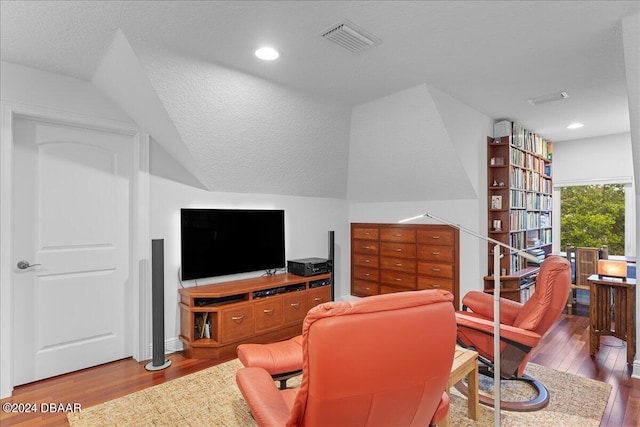 living room with hardwood / wood-style floors, lofted ceiling, and a textured ceiling