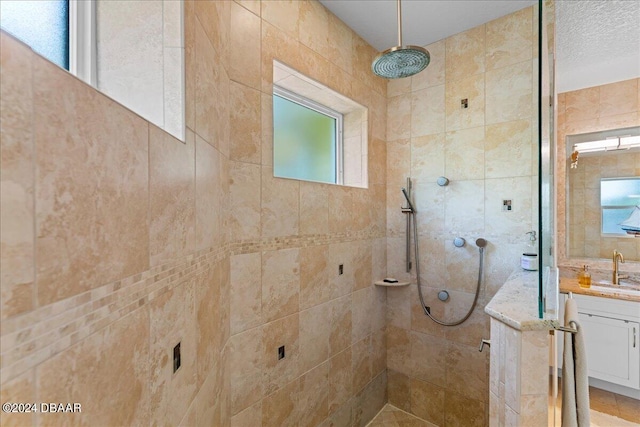 bathroom with tiled shower, a healthy amount of sunlight, and vanity