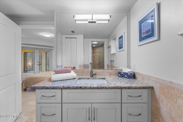 bathroom with vanity, a textured ceiling, an enclosed shower, and tile walls