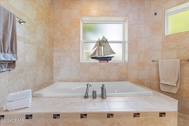 bathroom featuring tiled bath, plenty of natural light, and tile walls