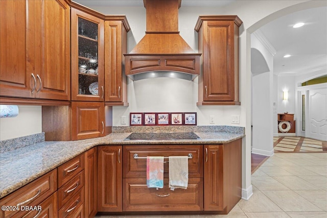 kitchen featuring black electric cooktop, light stone counters, ornamental molding, custom range hood, and light tile patterned flooring