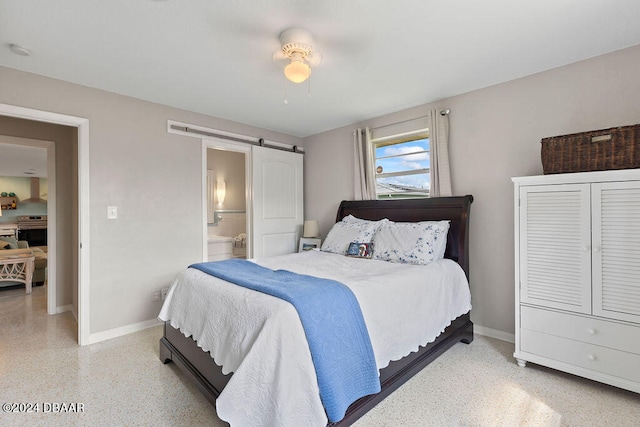 bedroom featuring connected bathroom, a barn door, and ceiling fan