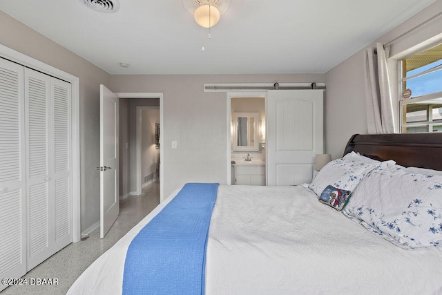 bedroom featuring a barn door, ensuite bathroom, and a closet