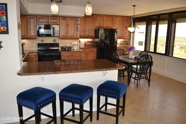 3580 S Ocean Shore Blvd Unit 905, Flagler Beach, FL 32136 - kitchen with black appliances, a peninsula, brown cabinets, and a kitchen bar