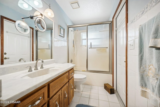 full bathroom featuring tile patterned flooring, vanity, bath / shower combo with glass door, and toilet