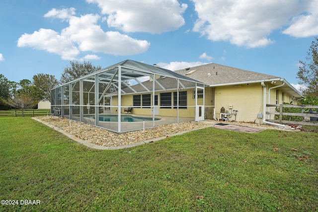 back of house with a lanai, a patio area, and a lawn