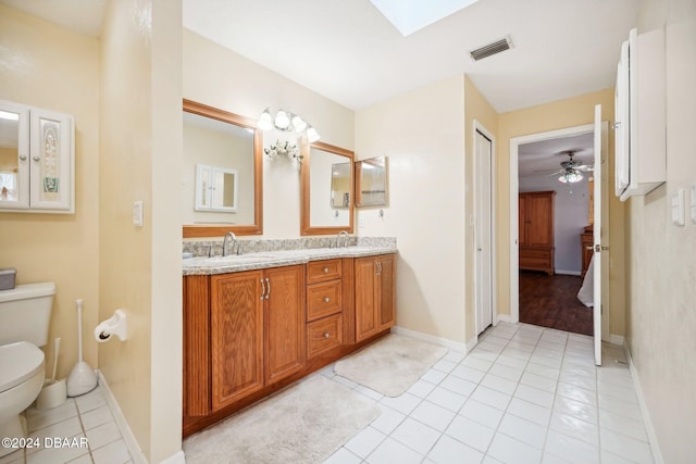 bathroom with a skylight, ceiling fan, tile patterned flooring, toilet, and vanity