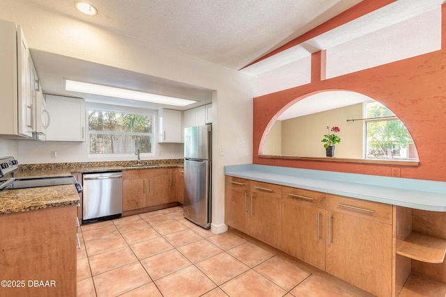 kitchen featuring white cabinets, a wealth of natural light, stainless steel appliances, and a textured ceiling