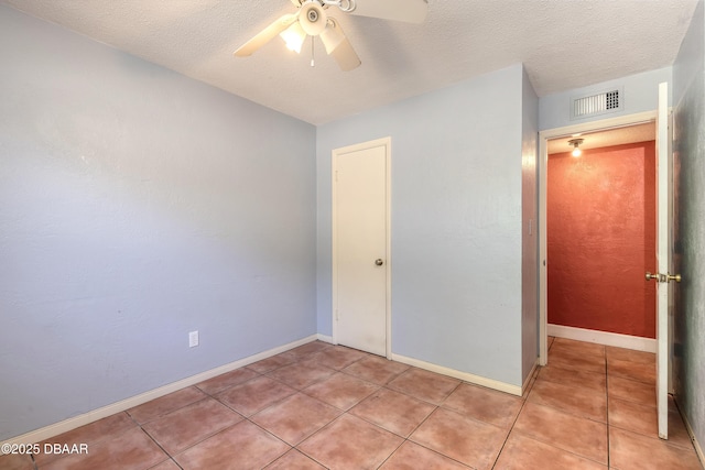 unfurnished bedroom featuring ceiling fan, a textured ceiling, and light tile patterned floors