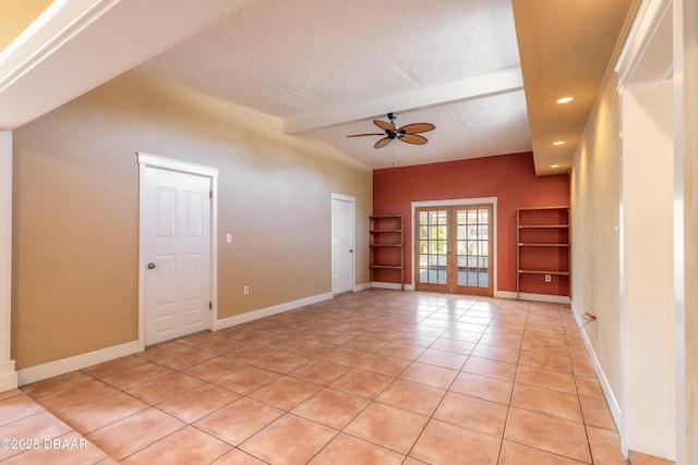 empty room with a textured ceiling, french doors, lofted ceiling with beams, ceiling fan, and light tile patterned floors