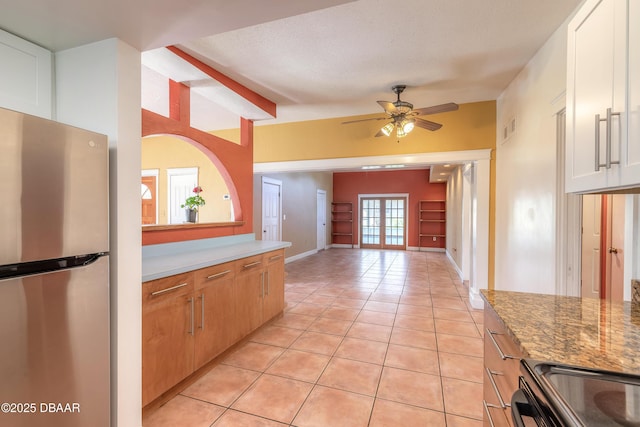 kitchen with light stone countertops, a textured ceiling, stainless steel fridge, ceiling fan, and light tile patterned floors