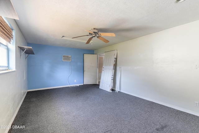 unfurnished bedroom featuring ceiling fan, a textured ceiling, a wall unit AC, and dark colored carpet