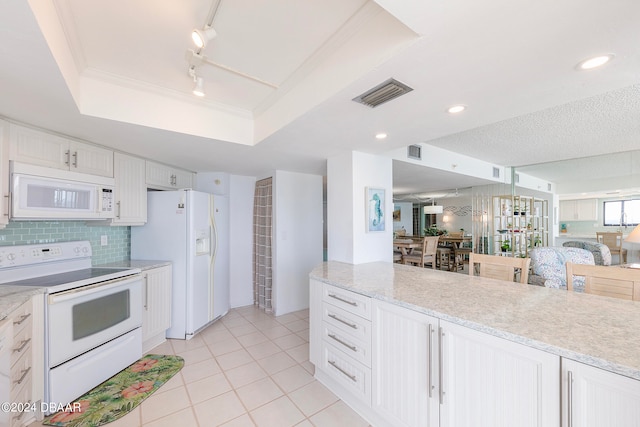 kitchen with light tile patterned flooring, a tray ceiling, white cabinetry, white appliances, and decorative light fixtures