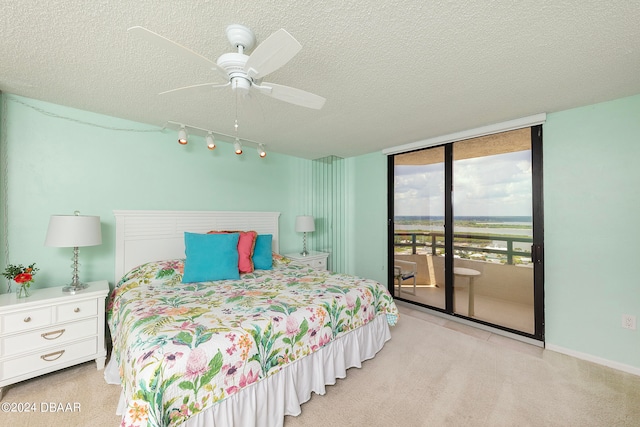 bedroom featuring light colored carpet, ceiling fan, a textured ceiling, and access to outside