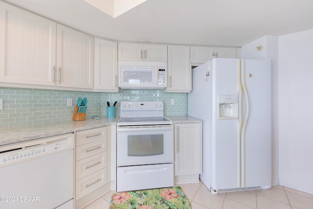 kitchen featuring tasteful backsplash, light stone counters, light tile patterned floors, white cabinets, and white appliances