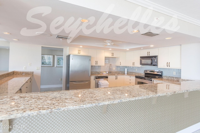 kitchen with stainless steel appliances, light stone countertops, white cabinets, and kitchen peninsula