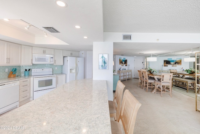 kitchen featuring light colored carpet, white cabinets, a textured ceiling, backsplash, and white appliances