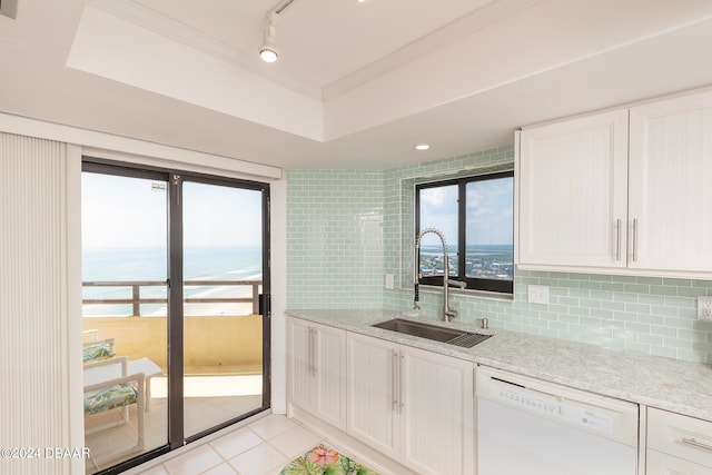 kitchen with sink, a water view, white dishwasher, light tile patterned floors, and decorative backsplash